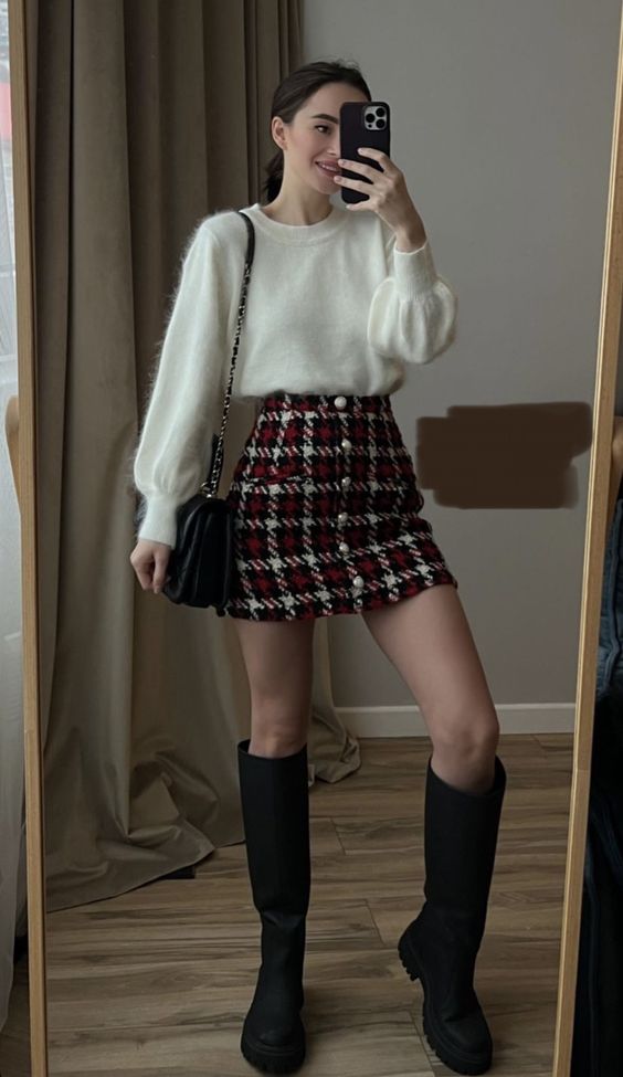 A girl taking mirror selfie wearing a warm oversized sweater and long boots