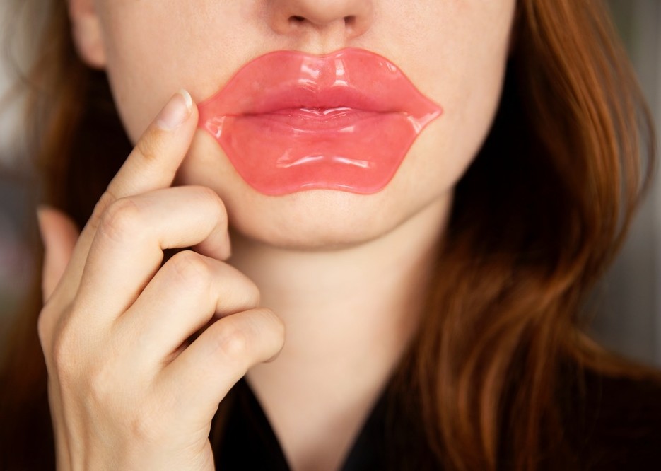 Woman using collagen lip mask for dry and chapped lips. 