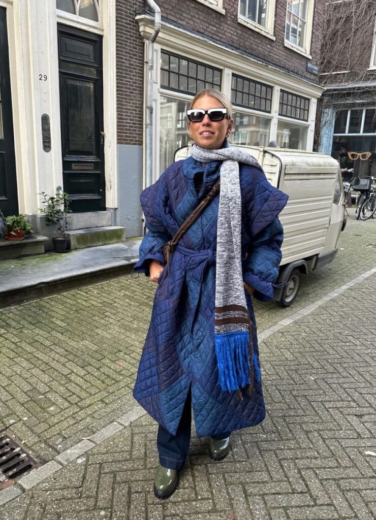 Model showing of dark blue padded coat long coat on the streets of Amsterdam