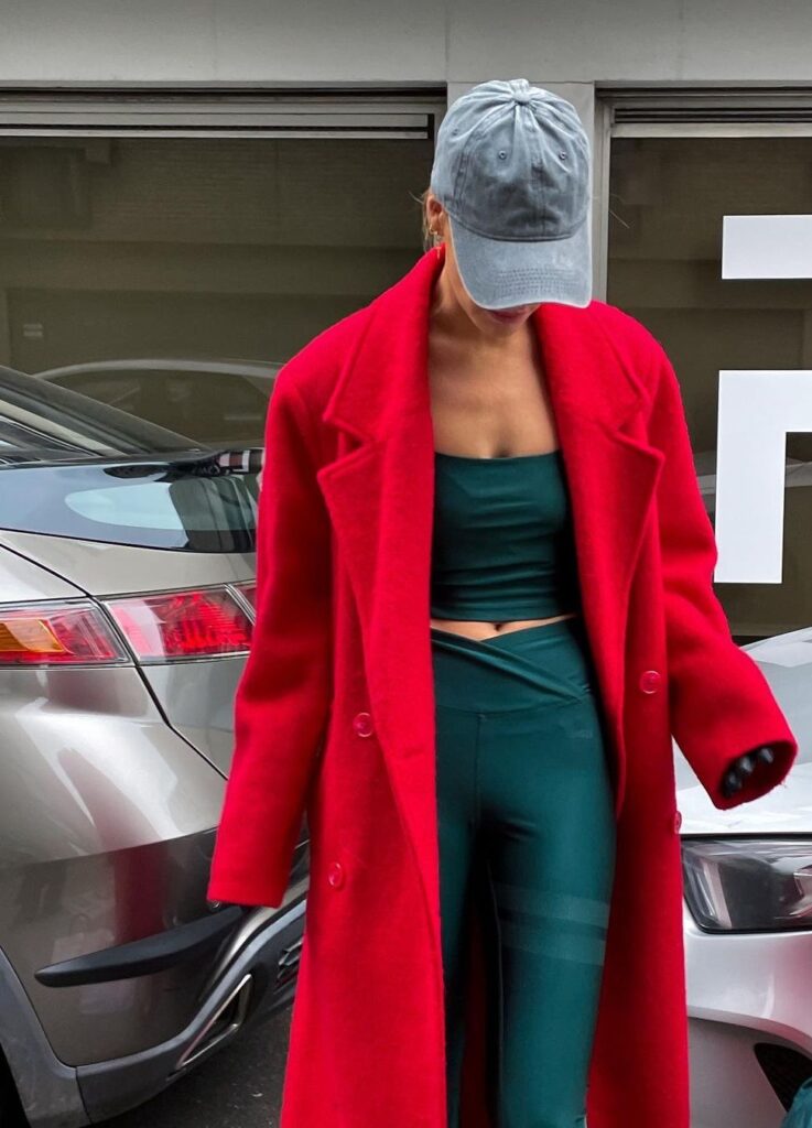 A women showing of red color men's cut long coat that fits perfectly with sportswear