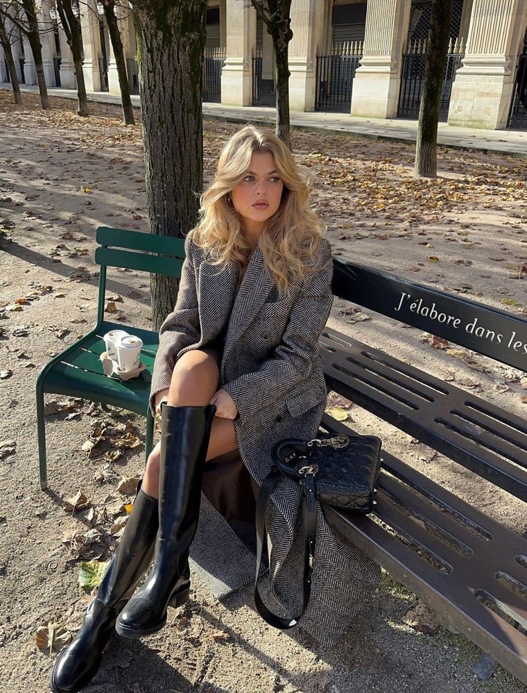 Girl wearing long coat having a peaceful time on bench